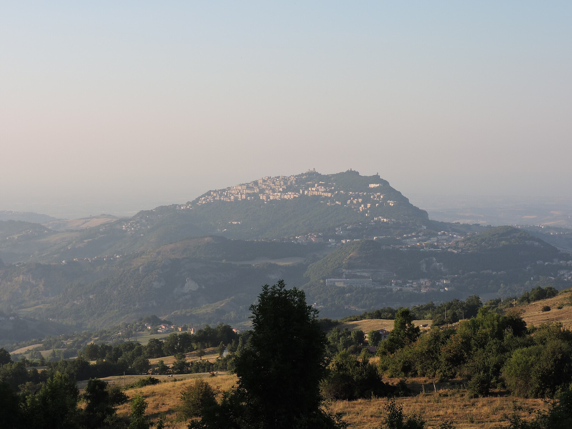 Monte Titano and the Three Towers of San Marino at sunset, seen from the Valmarecchia valley floor.